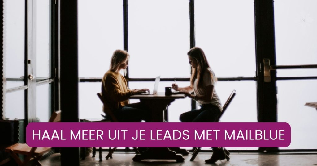 Twee vrouwen werken samen aan tafel op laptops terwijl ze praten over hun klantreis en e-mailmarketing met Mailblue.